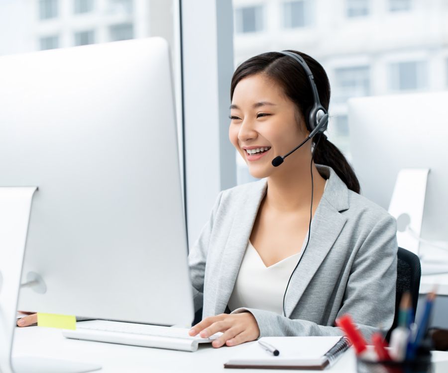 Image of a woman seated at her desk completing online learning course. She is wearing a headset